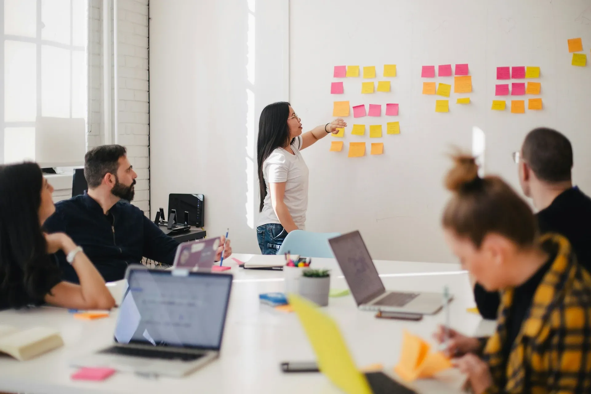 Vue plongeante : varios collaborateurs joignent los mains au centre d'un cercle sur una table de réunion — espíritu d'equipo y protección sociale en empresa